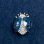 (20/25 mm) Sun-shaped brooch in light metal, adorned with stones, blue enamel
